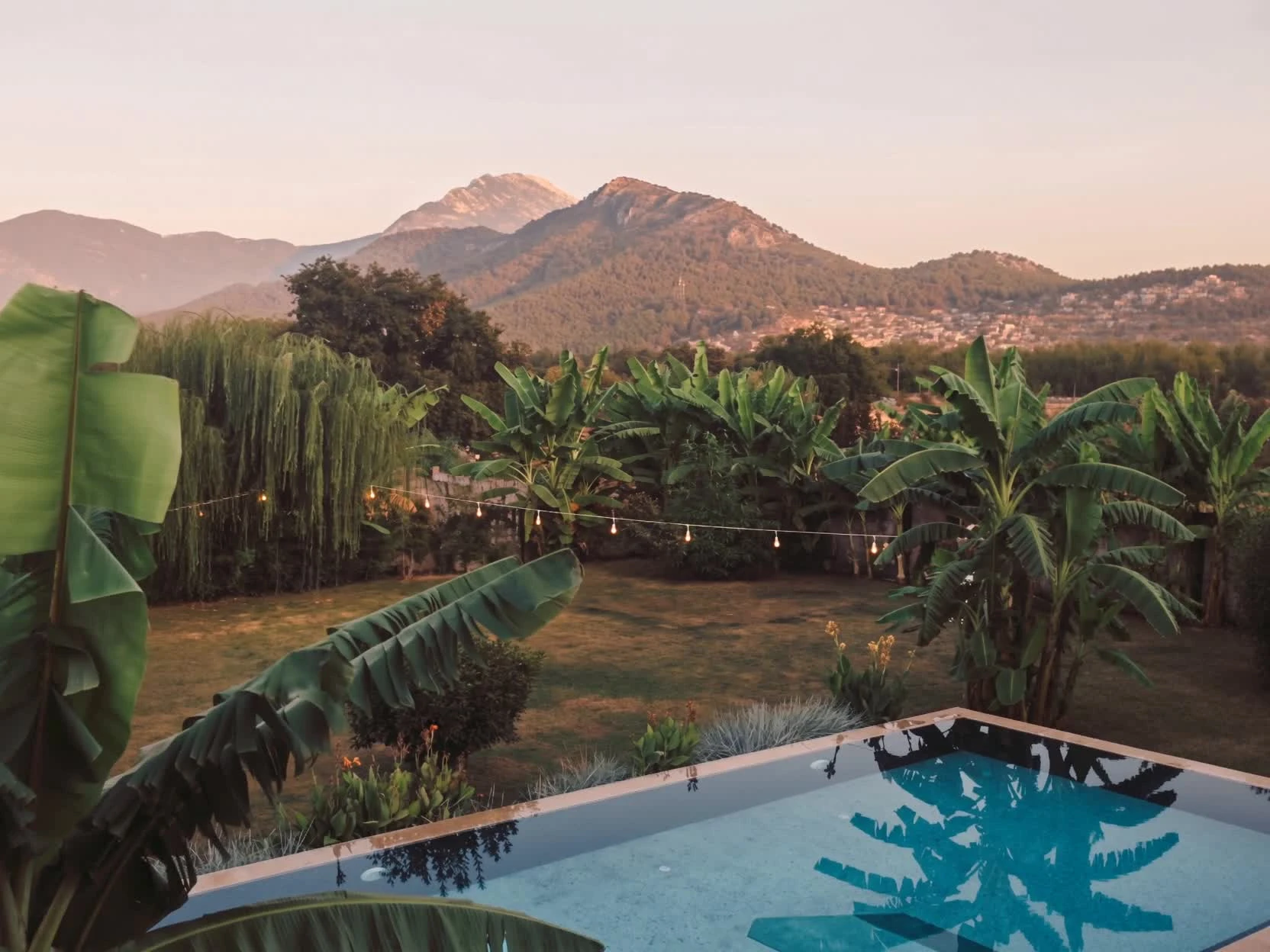 Garden and pool with banana planting, willow and pine-covered hills, from the supplied Kayaköy valley clip.